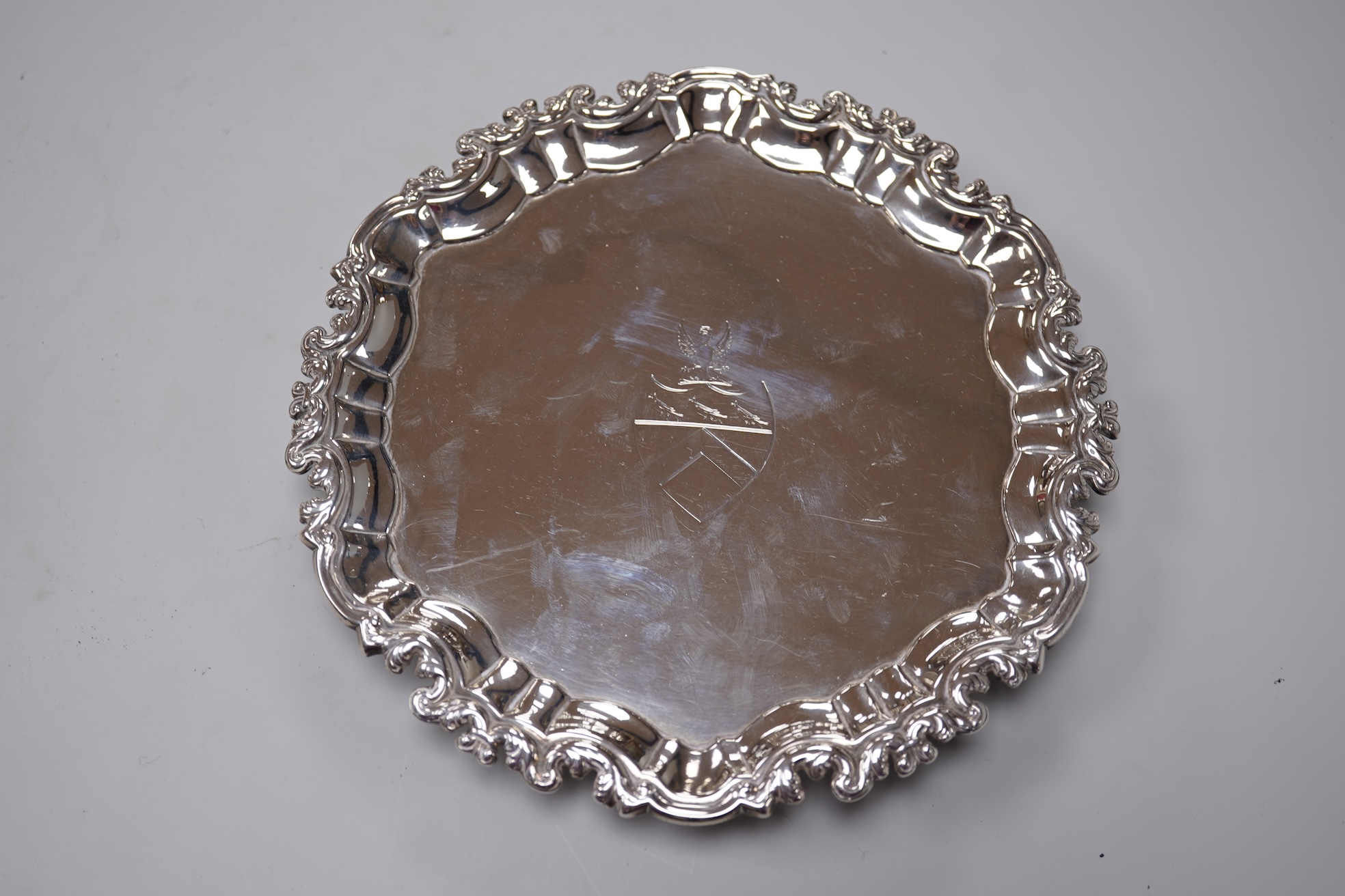 A George II silver card waiter, (with Howard Tripp crest?), of shaped circular form, on three scroll feet, maker's mark rubbed, London, 1740, 17.9cm, 9.4oz.
